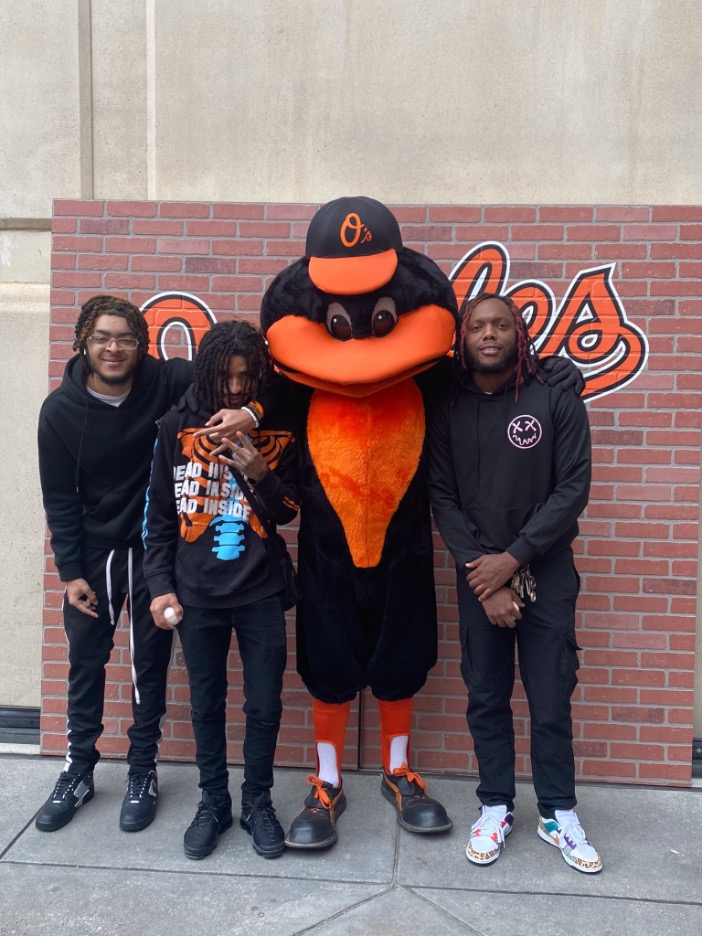 Three youth posing with the Orioles mascot 