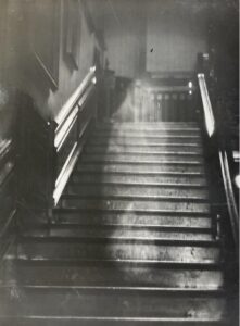 Black and white photo of stairs and a ghostly figure