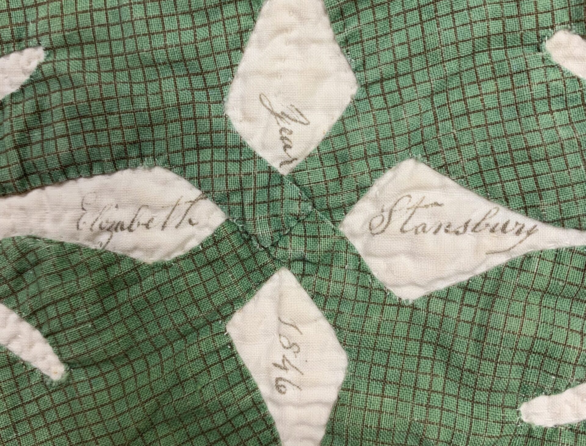 Green and white quilt with writing